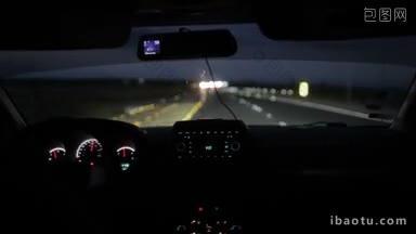 在夜间或清晨驾驶一辆汽车，从内部发光的仪表盘和迎面而来的车辆的模糊灯光